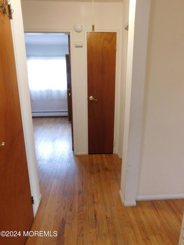 hall featuring light wood-type flooring and a baseboard heating unit