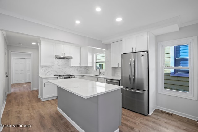 kitchen featuring white cabinets, appliances with stainless steel finishes, a center island, and sink