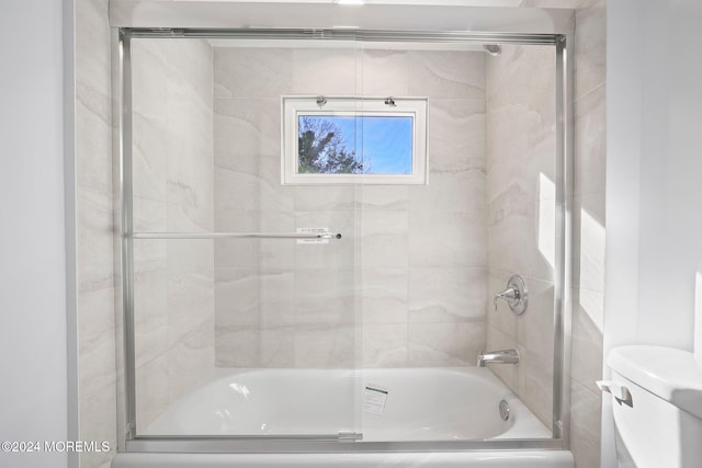 bathroom with bath / shower combo with glass door and toilet