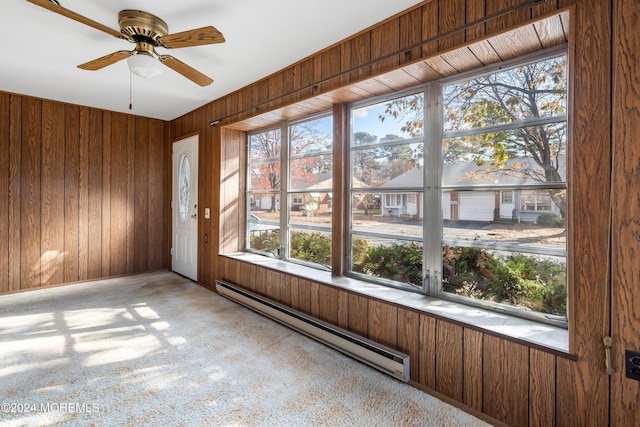 unfurnished sunroom featuring a baseboard radiator and ceiling fan