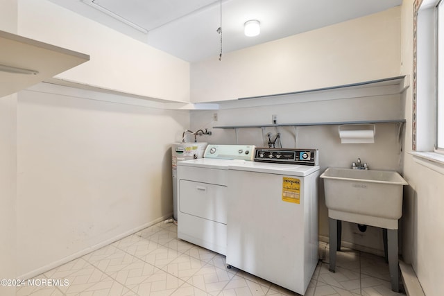 clothes washing area with electric water heater, sink, washer / dryer, and light tile patterned floors