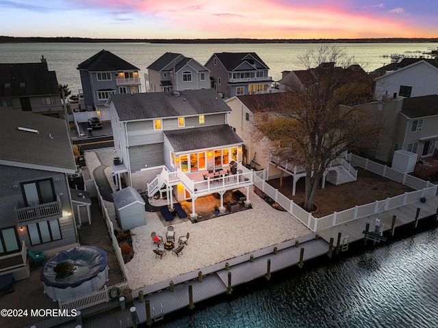 back house at dusk with a water view and a patio area