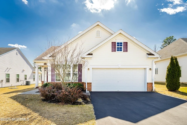 traditional home with brick siding, an attached garage, aphalt driveway, and central AC