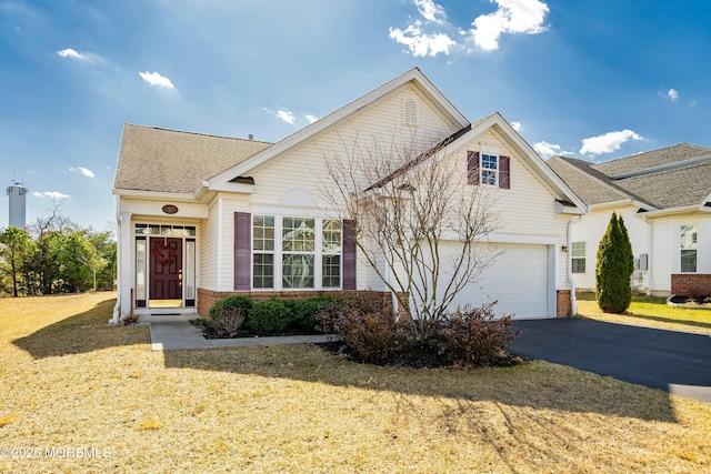 view of front of home featuring roof with shingles, a front lawn, a garage, aphalt driveway, and brick siding