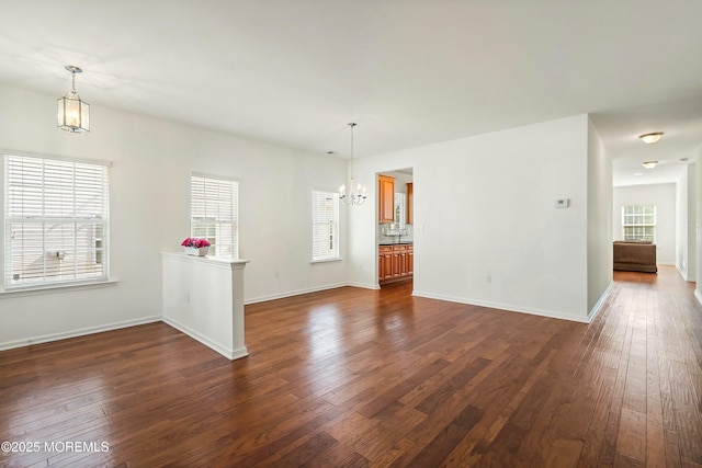 unfurnished room featuring baseboards, a notable chandelier, and dark wood-style flooring