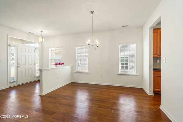 unfurnished dining area with an inviting chandelier, dark wood-style floors, baseboards, and visible vents