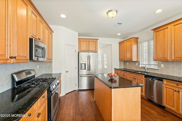 kitchen with visible vents, dark wood finished floors, a sink, appliances with stainless steel finishes, and a center island