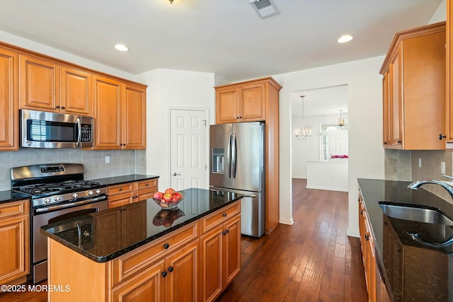 kitchen featuring visible vents, a sink, stainless steel appliances, dark wood-type flooring, and backsplash