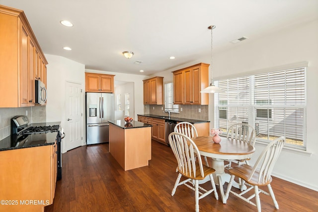 kitchen with visible vents, a sink, a center island, stainless steel appliances, and dark wood-style flooring