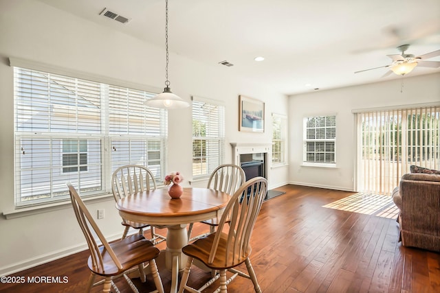 dining space featuring visible vents, a fireplace, dark wood-style flooring, and baseboards