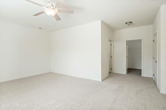 spare room featuring baseboards, a ceiling fan, visible vents, and light carpet