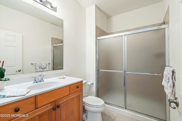 bathroom with vanity, tile patterned floors, toilet, and a stall shower