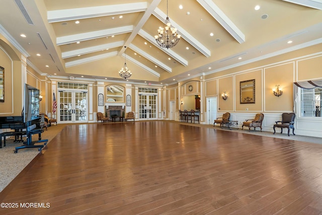 interior space with a fireplace, french doors, crown molding, a decorative wall, and a chandelier