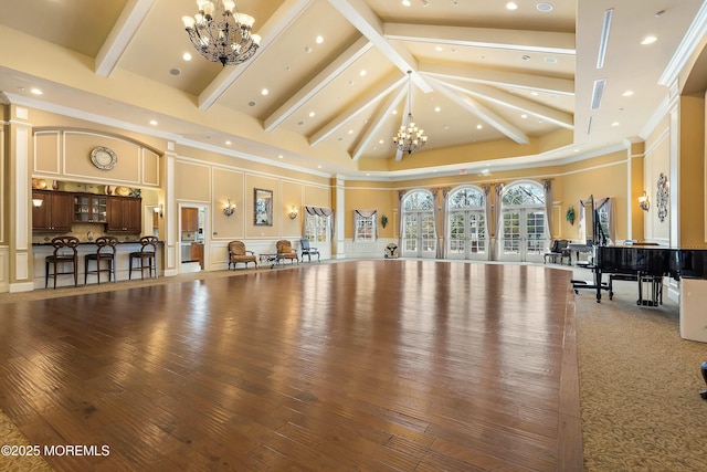 interior space with recessed lighting, high vaulted ceiling, an inviting chandelier, and a decorative wall