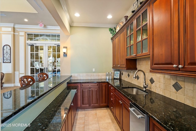 kitchen featuring crown molding, dark stone countertops, backsplash, and a sink