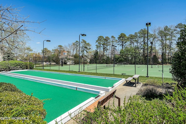 view of community featuring a tennis court and fence