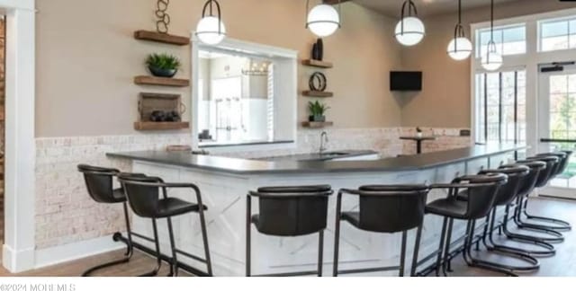 kitchen with pendant lighting, kitchen peninsula, sink, and a breakfast bar