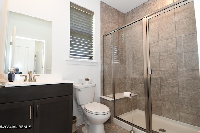 bathroom featuring a shower with shower door, vanity, and toilet