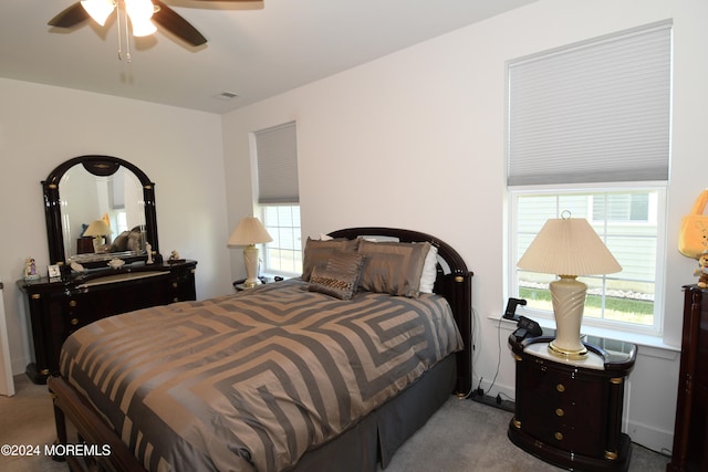 carpeted bedroom with ceiling fan and multiple windows