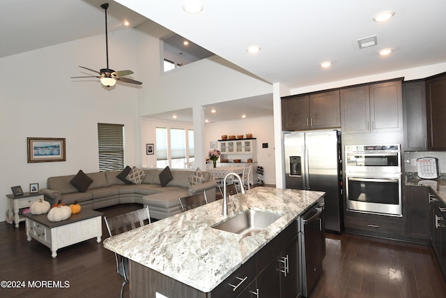 kitchen featuring stainless steel appliances, a center island with sink, sink, a breakfast bar area, and high vaulted ceiling