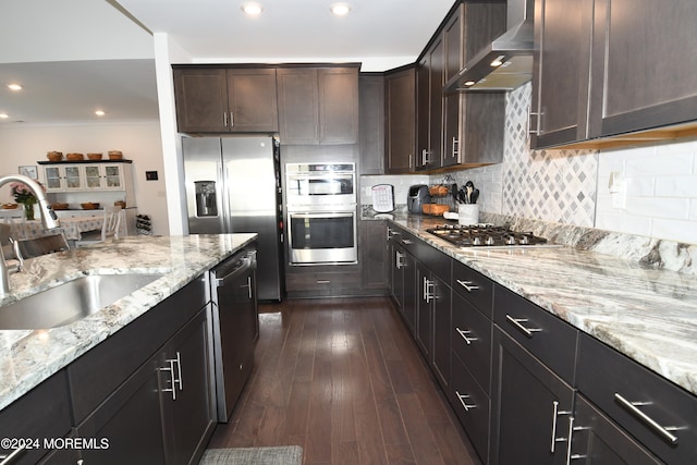 kitchen with stainless steel appliances, dark brown cabinetry, sink, dark wood-type flooring, and wall chimney range hood