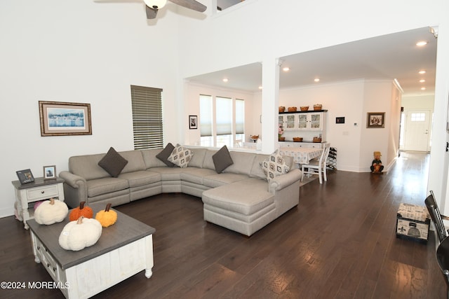 living room with ornamental molding, ceiling fan, dark hardwood / wood-style floors, and a towering ceiling