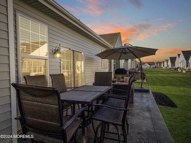 patio terrace at dusk featuring a yard