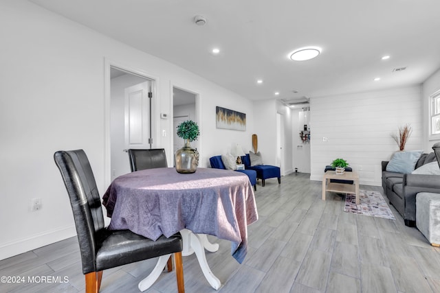 dining area featuring light wood-type flooring and wood walls