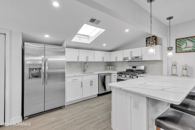 kitchen with kitchen peninsula, appliances with stainless steel finishes, white cabinetry, and lofted ceiling with skylight