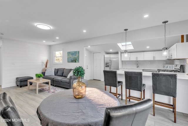 dining room with a skylight, wood walls, light hardwood / wood-style flooring, and sink