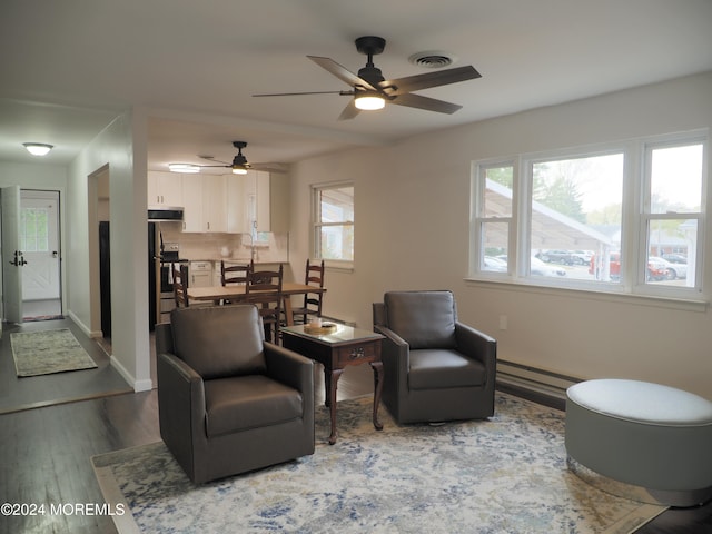 living room with hardwood / wood-style flooring, ceiling fan, and a baseboard heating unit