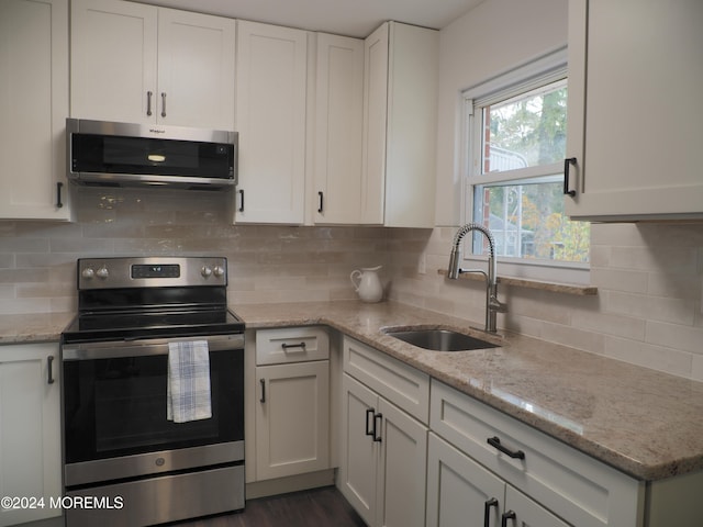 kitchen featuring stainless steel appliances, sink, backsplash, light stone countertops, and white cabinetry