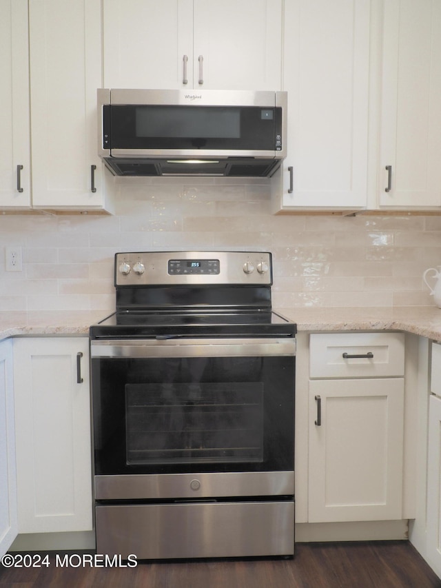 kitchen with white cabinets, appliances with stainless steel finishes, and exhaust hood