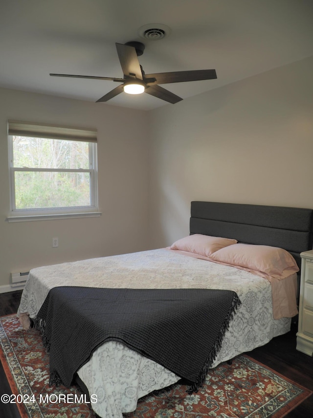 bedroom with baseboard heating, ceiling fan, and dark hardwood / wood-style floors