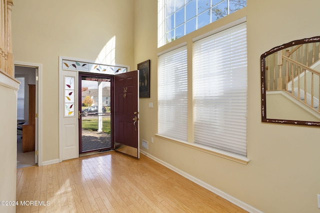 entrance foyer with light hardwood / wood-style floors and a towering ceiling