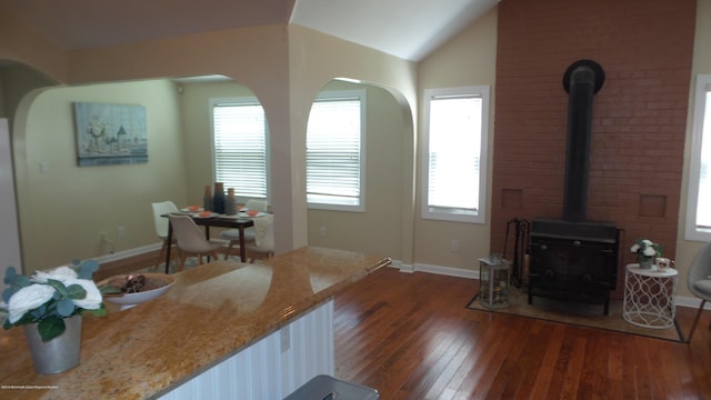 living room with vaulted ceiling, dark hardwood / wood-style flooring, and a wood stove