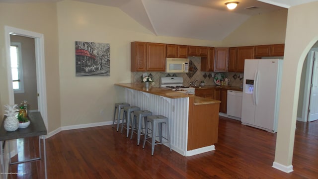 kitchen with a kitchen bar, kitchen peninsula, decorative backsplash, white appliances, and lofted ceiling