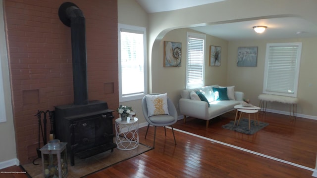 living room featuring lofted ceiling, a wood stove, and hardwood / wood-style flooring