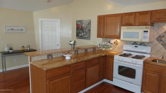 kitchen featuring tasteful backsplash, kitchen peninsula, dark hardwood / wood-style flooring, and white appliances