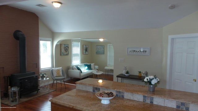 living room with a wood stove, dark hardwood / wood-style floors, and vaulted ceiling