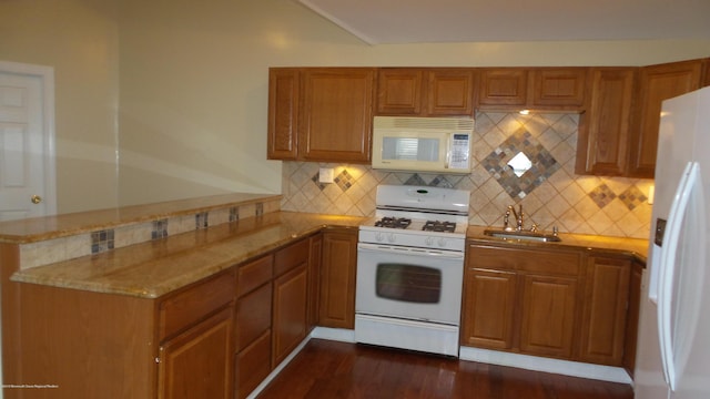 kitchen featuring light stone countertops, white appliances, tasteful backsplash, sink, and kitchen peninsula