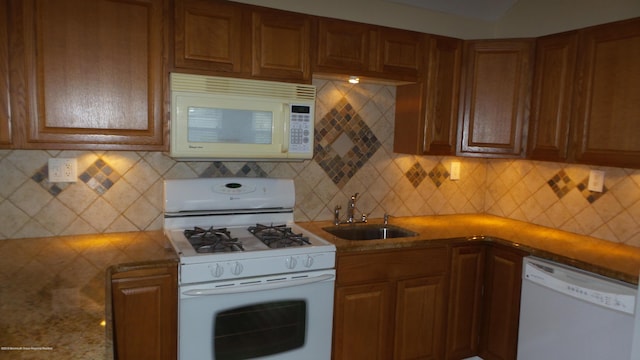 kitchen featuring backsplash, sink, and white appliances