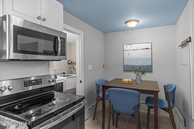 kitchen featuring white cabinets, appliances with stainless steel finishes, wood-type flooring, and washing machine and clothes dryer