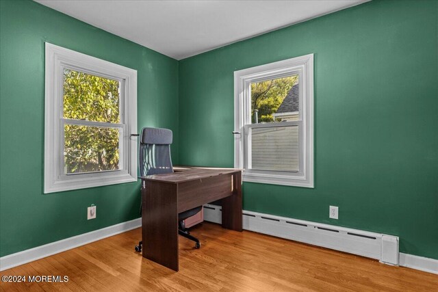 home office featuring a baseboard radiator and light hardwood / wood-style flooring