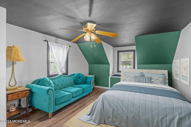 bedroom featuring hardwood / wood-style floors, multiple windows, and lofted ceiling