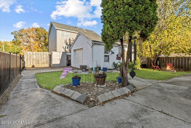 rear view of house featuring a garage, a lawn, and an outdoor structure