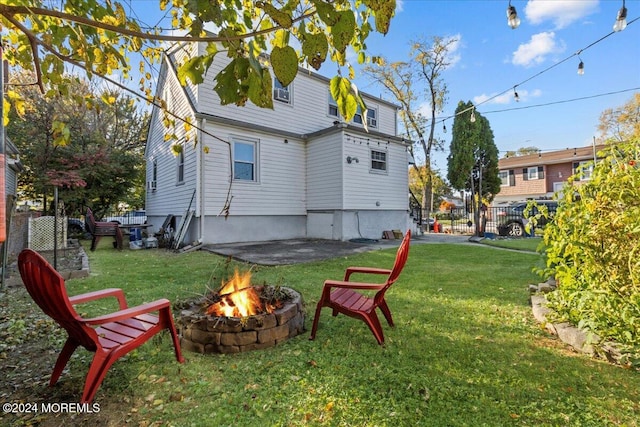 back of property featuring an outdoor fire pit and a lawn