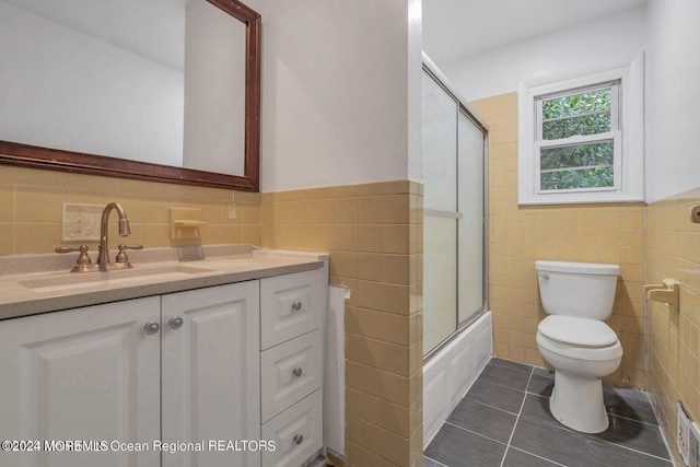 full bathroom with tile walls, combined bath / shower with glass door, and toilet