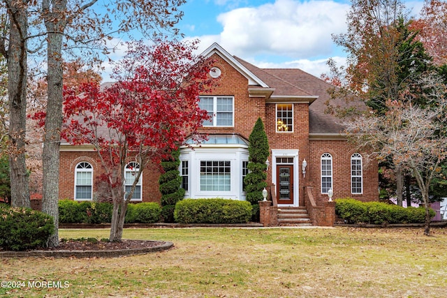 colonial inspired home featuring a front lawn