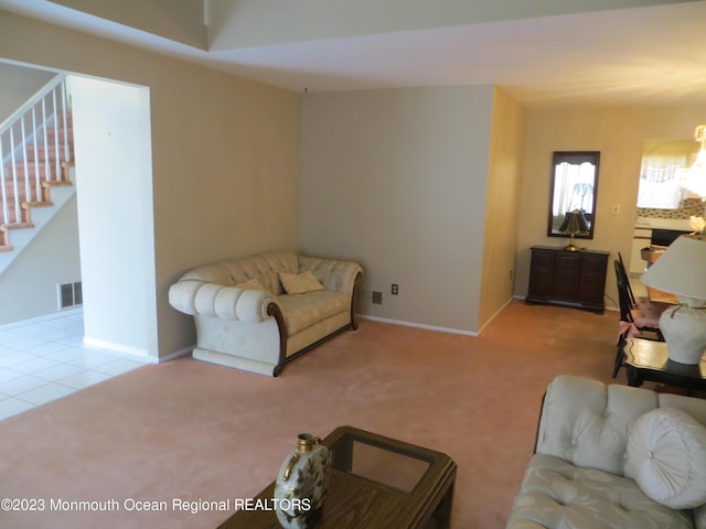 carpeted living area featuring tile patterned floors, visible vents, baseboards, and stairs